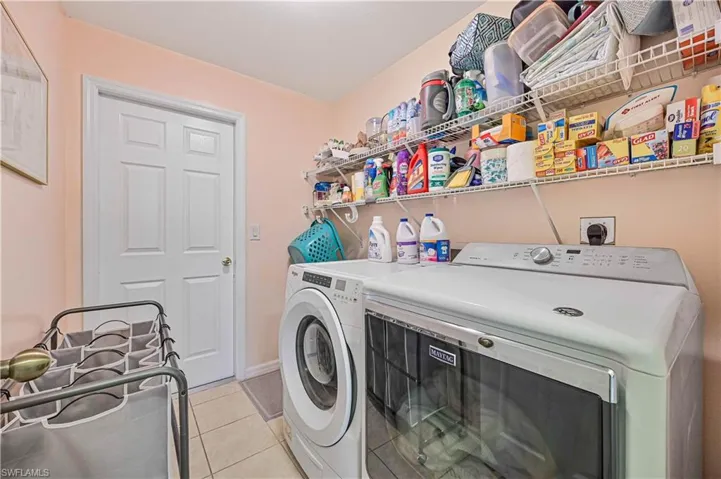 Laundry area featuring washing machine and dryer and light tile floors with lots of storage space.