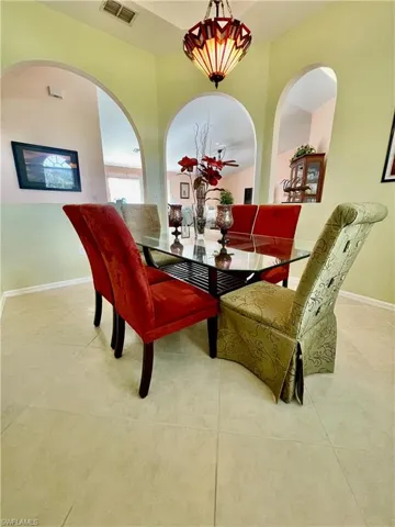 Dining space featuring light tile patterned flooring and an artistic chandelier.