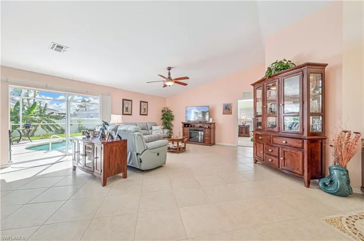 Living room with light tile flooring, vaulted ceiling, and ceiling fan