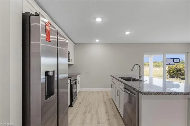 Kitchen with sink, white cabinets, stainless steel appliances, and stone counters
