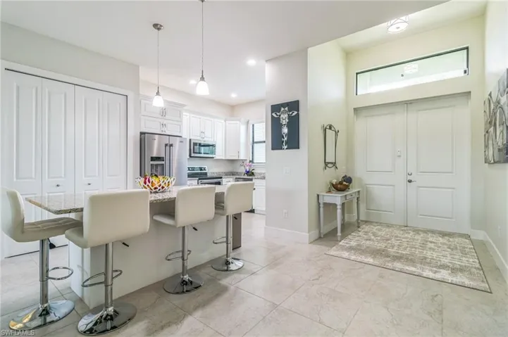 Kitchen with appliances with stainless steel finishes, a kitchen bar, white cabinetry, pendant lighting, and a center island