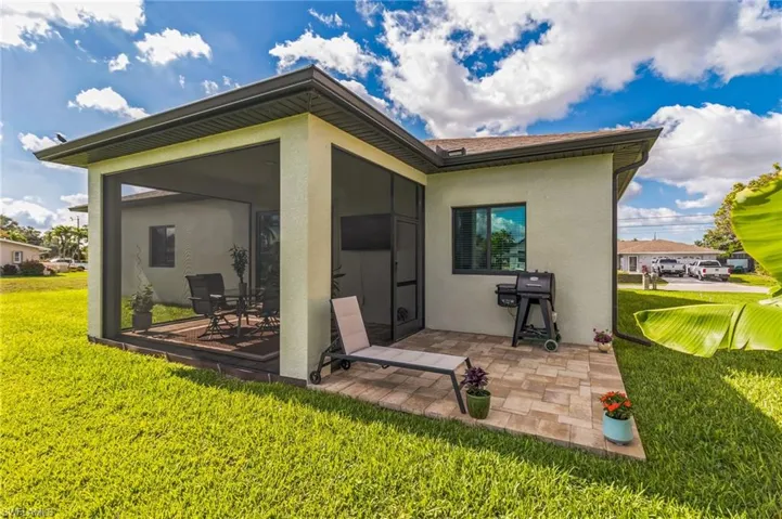 Back of house featuring stucco siding, a patio area, a lawn, and a sunroom