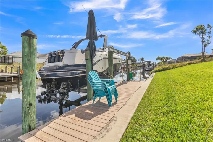 Dock with boat lift, a lawn, and a water view