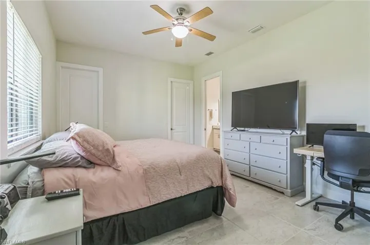 Bedroom featuring a ceiling fan, an office area, and connected bathroom