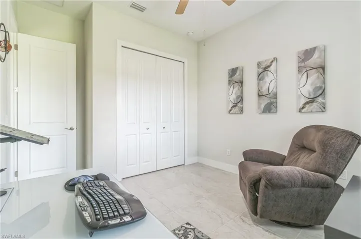 Living area featuring a ceiling fan, baseboards, and light marble finish floors