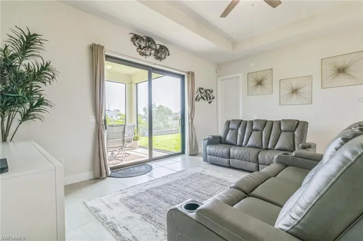 Tiled living area with ceiling fan and baseboards