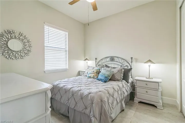 Bedroom featuring ceiling fan, light tile patterned flooring, and baseboards