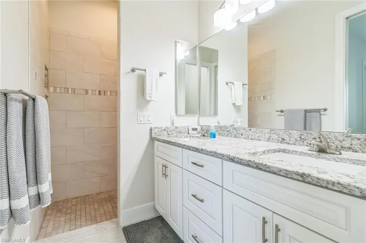 Bathroom with a walk in shower, double vanity, and tile patterned floors