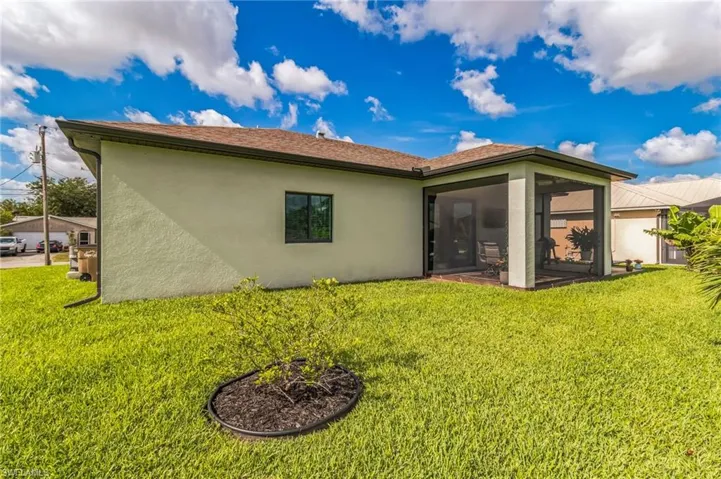 Rear view of house with stucco siding, a sunroom, and a lawn