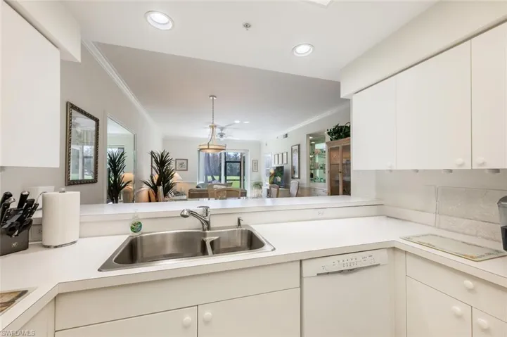 Kitchen with crown molding, white dishwasher, kitchen peninsula, and sink