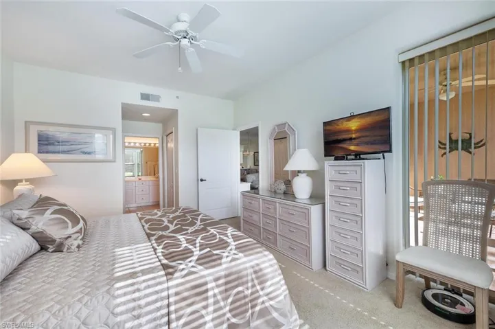 Carpeted bedroom with connected bathroom and ceiling fan