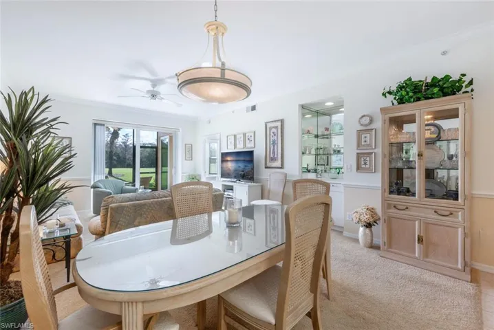 Carpeted dining area with crown molding and ceiling fan