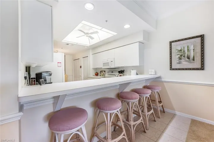 Kitchen featuring range, a skylight, a kitchen breakfast bar, kitchen peninsula, and white cabinets
