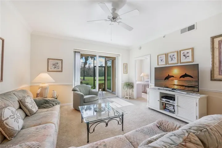Carpeted living room featuring crown molding and ceiling fan