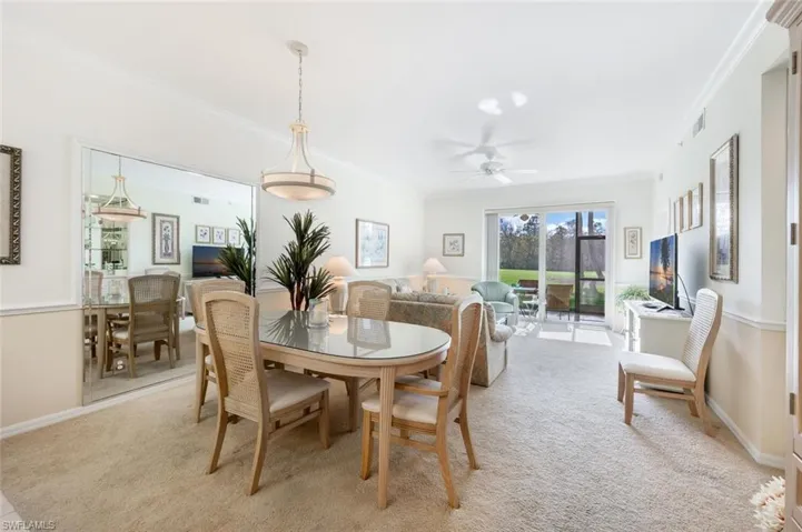 Dining area with ceiling fan, ornamental molding, and light carpet
