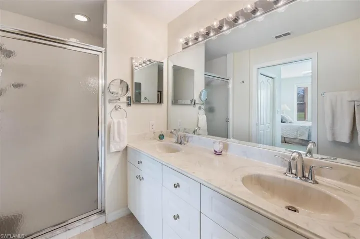 Bathroom with an enclosed shower, vanity, and tile patterned flooring