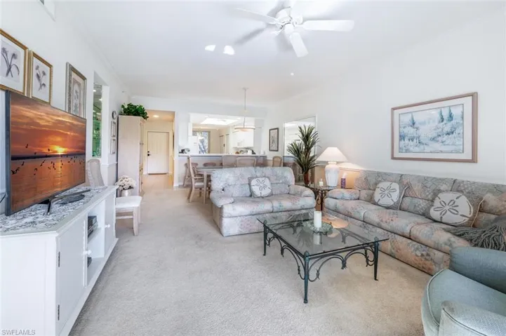 Living room with crown molding, light carpet, and ceiling fan