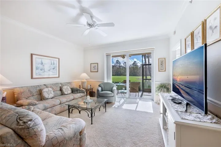 Living room with light carpet, ornamental molding, and ceiling fan