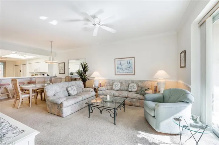 Carpeted living room featuring crown molding and ceiling fan