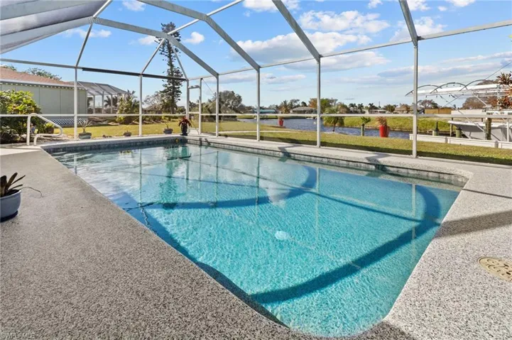 View of swimming pool featuring a patio area, a lawn, and a lanai