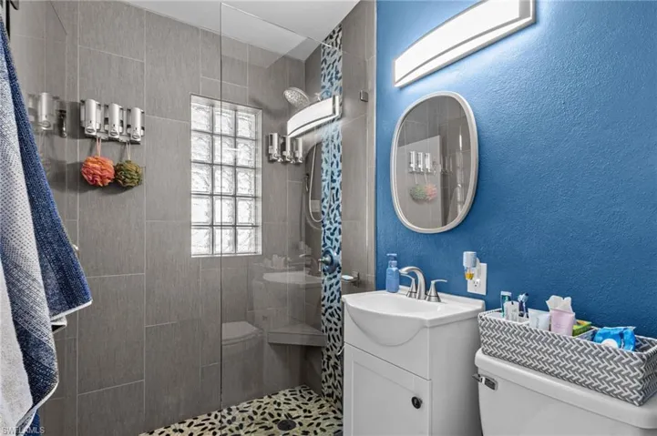 Bathroom with vanity, a tile shower, and toilet