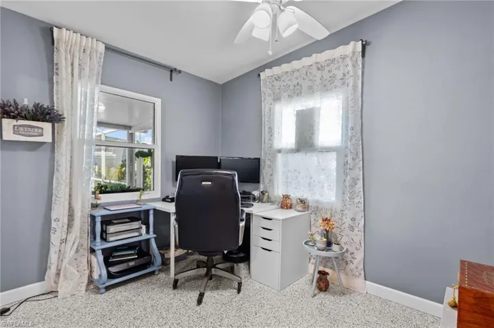 Carpeted home office featuring lofted ceiling and ceiling fan