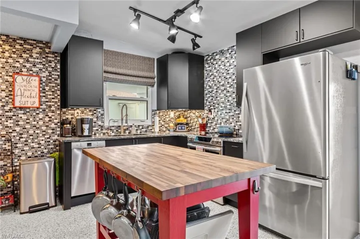 Kitchen with wooden counters, sink, appliances with stainless steel finishes, and tasteful backsplash