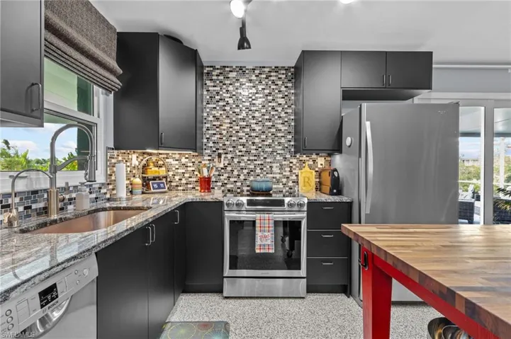 Kitchen with sink, butcher block counters, stainless steel appliances, and backsplash