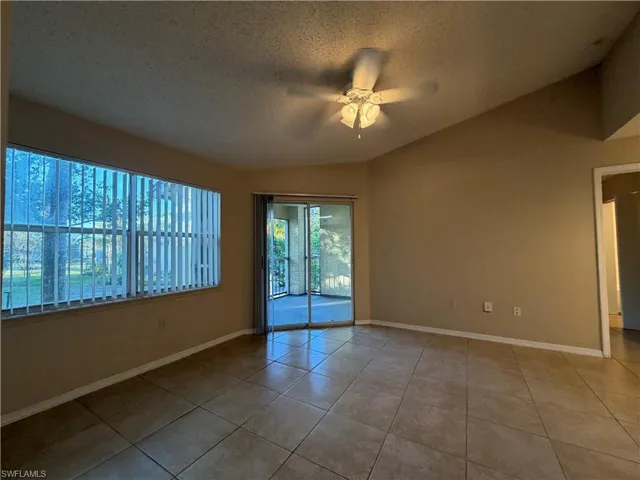 Tiled spare room featuring a ceiling fan and baseboards