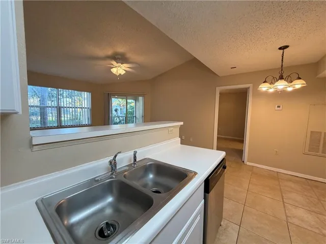 Kitchen featuring light countertops, white cabinets, dishwasher, light tile patterned flooring, and a ceiling fan