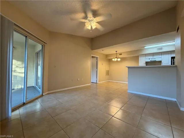 Unfurnished living room featuring a textured ceiling, a ceiling fan, hanging lights, and light tile patterned flooring