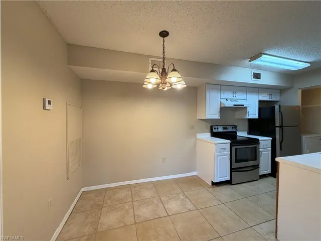 Kitchen featuring white cabinetry, light countertops, stainless steel electric range, suspended lighting, and a textured ceiling
