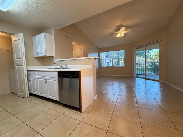 Kitchen with a ceiling fan, white cabinets, dishwasher, open floor plan, and light countertops