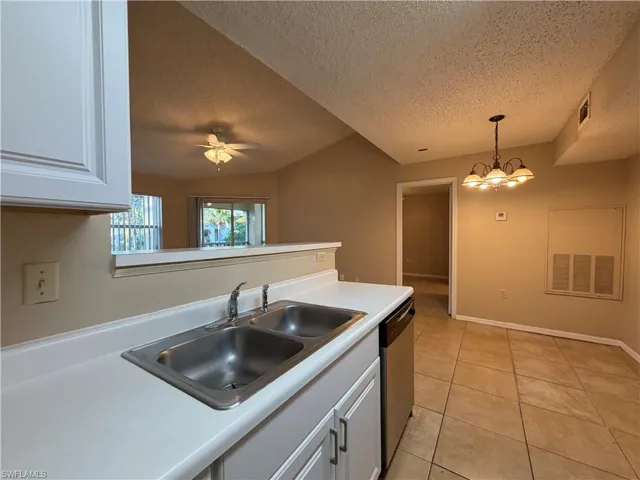 Kitchen featuring white cabinets, light countertops, stainless steel dishwasher, light tile patterned floors, and ceiling fan