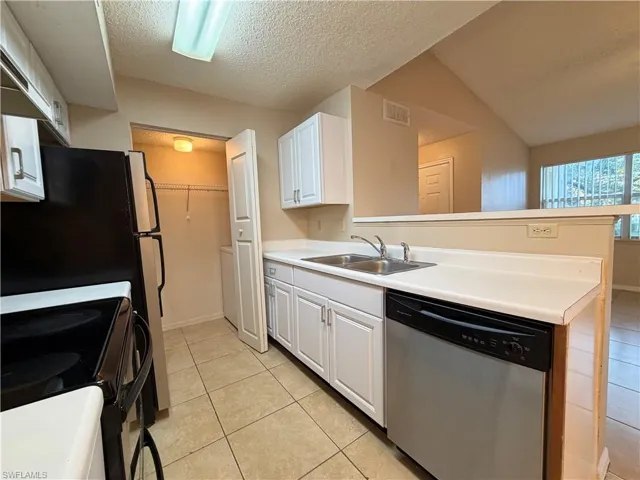 Kitchen featuring stainless steel appliances, white cabinetry, light tile patterned flooring, and light countertops