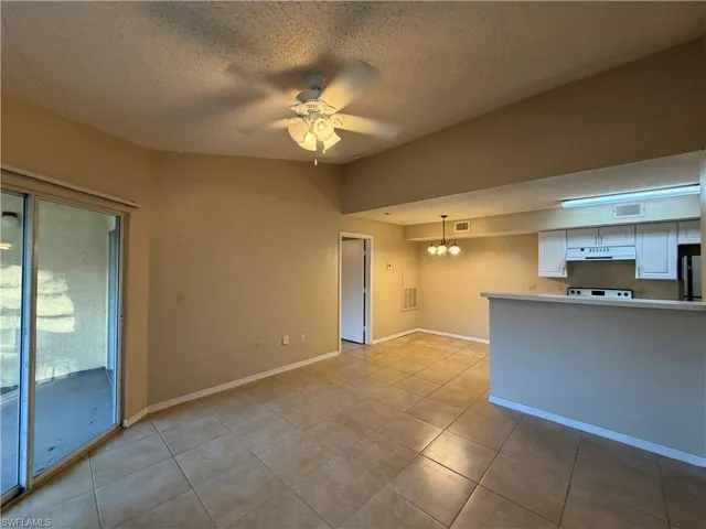 Unfurnished living room with ceiling fan, suspended lighting, and light tile patterned floors