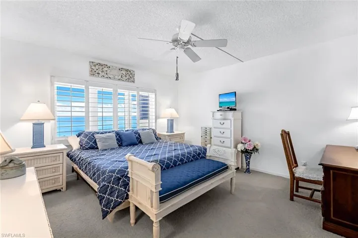 Carpeted bedroom with a textured ceiling and ceiling fan