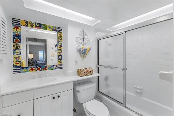 Full bathroom featuring combined bath / shower with glass door, toilet, and vanity