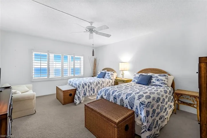 Bedroom with a textured ceiling, ceiling fan, and light colored carpet