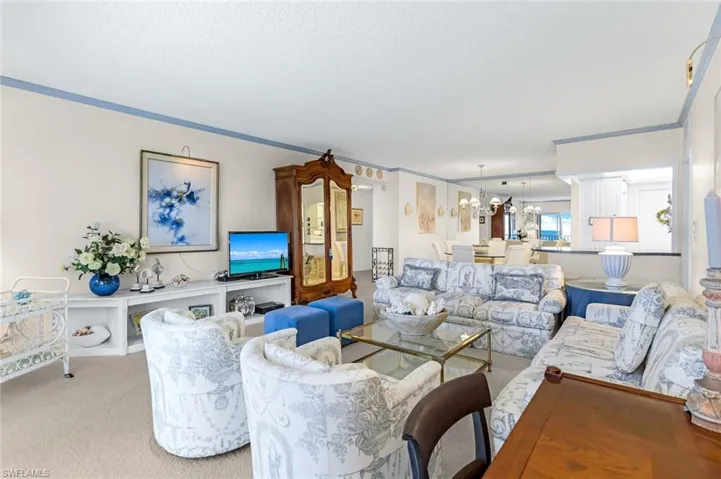 Carpeted living room with a notable chandelier and crown molding