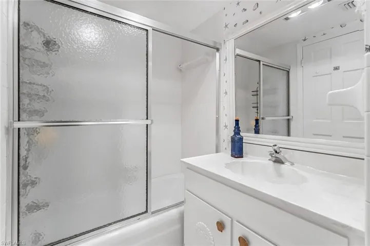 Bathroom featuring vanity and shower / bath combination with glass door