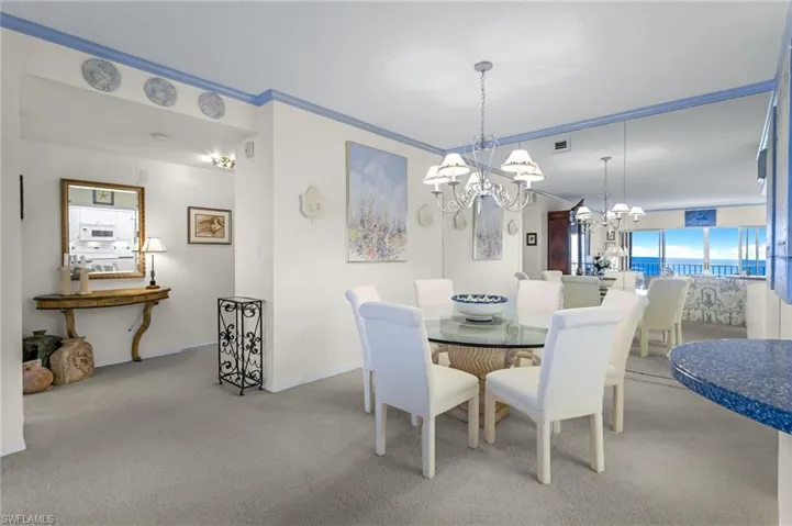 Dining space with an inviting chandelier, ornamental molding, and carpet flooring