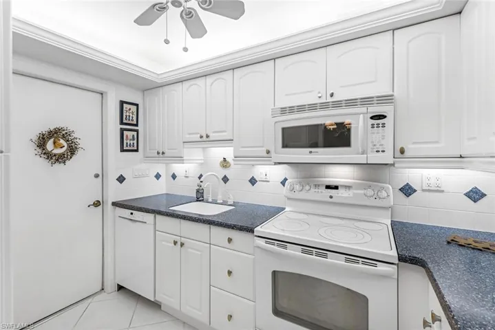 Kitchen with white cabinetry, white appliances, backsplash, ceiling fan, and sink
