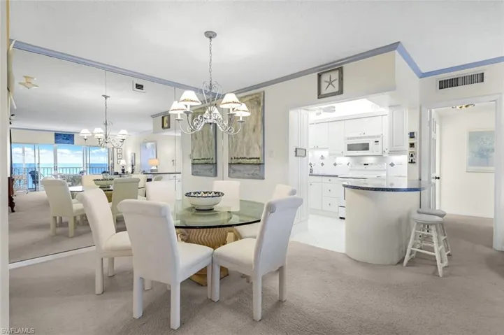 Carpeted dining room with crown molding and a chandelier