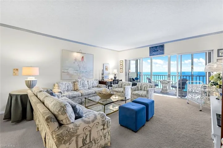 Carpeted living room featuring crown molding, a textured ceiling, and a water view