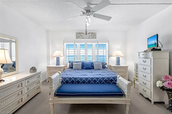 Carpeted bedroom featuring a textured ceiling and ceiling fan