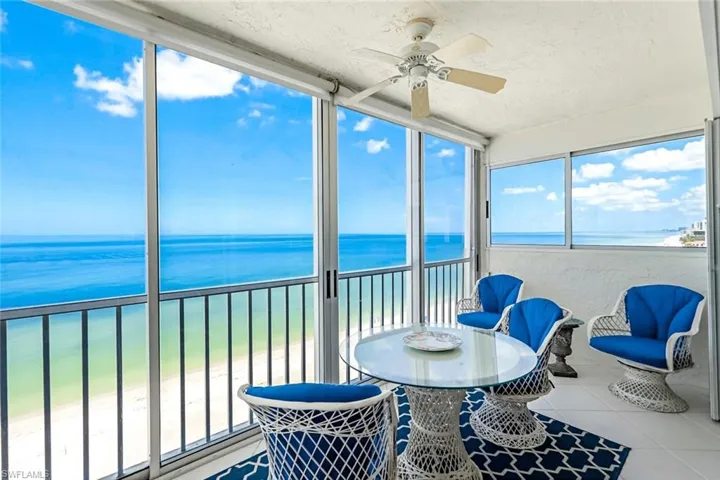 Sunroom featuring a water view, a view of the beach, and ceiling fan