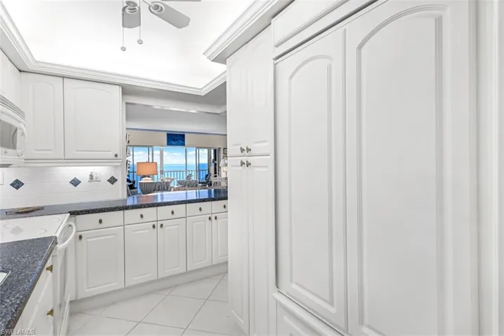 Kitchen with ceiling fan, white cabinetry, tasteful backsplash, and white appliances