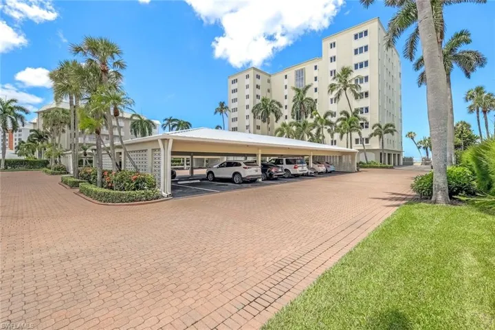 View of vehicle parking featuring a lawn and a carport