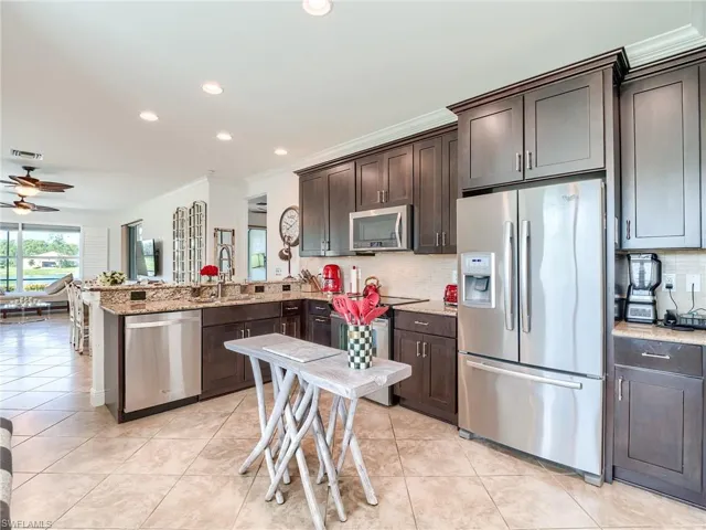Kitchen featuring ceiling fan, kitchen peninsula, backsplash, and appliances with stainless steel finishes